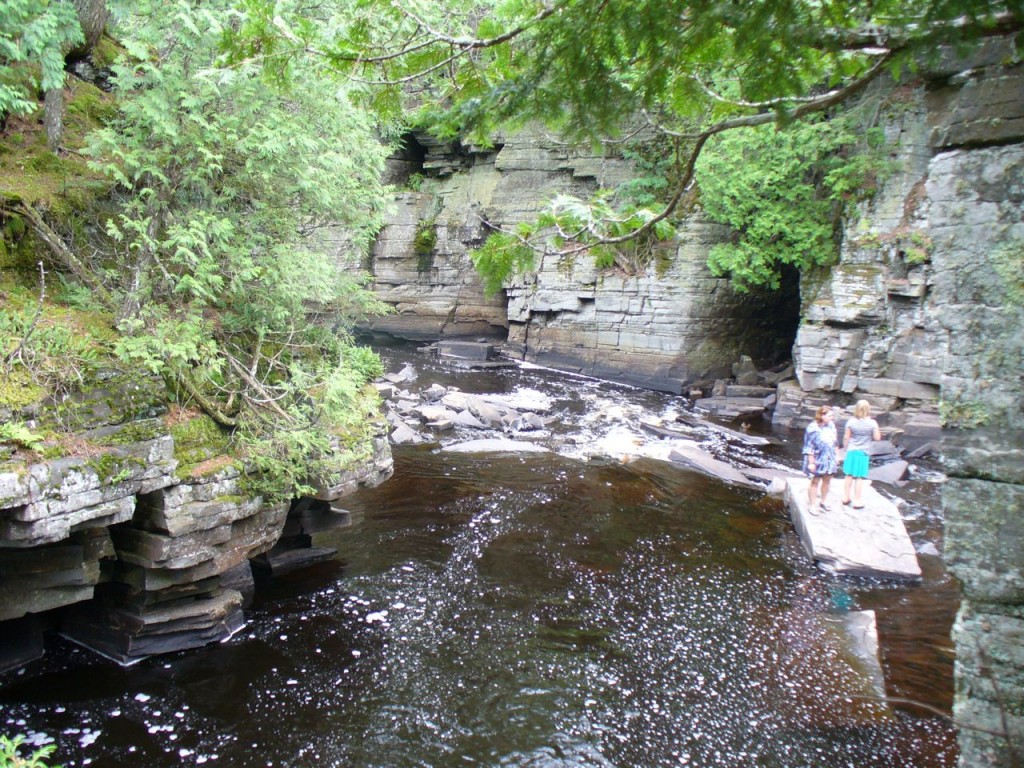 People standing on a rock down the falls.