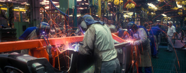 Workers welding on an automobile assembly line.