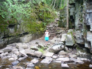 Lila standing on rocky riverbank.