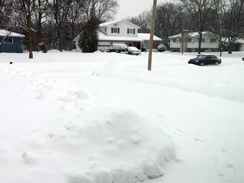 Snowy street and snowbanks along driveways